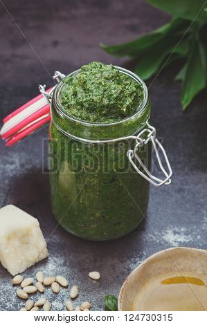 Wild garlic pesto. Ramsons or wild garlic pesto in preserving jar and ingredients. Macro, selective focus, vintage toned image, blank space, view from above