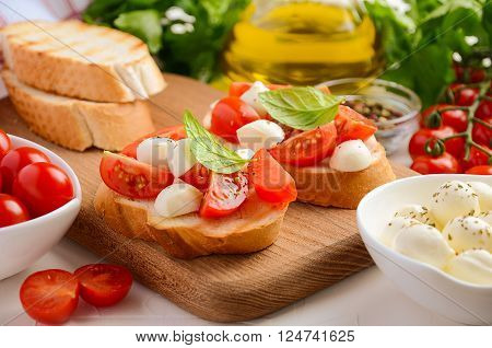 Bruschetta with cherry tomatoes and mozzarella on wooden board. Horizontal permission. Selective focus.