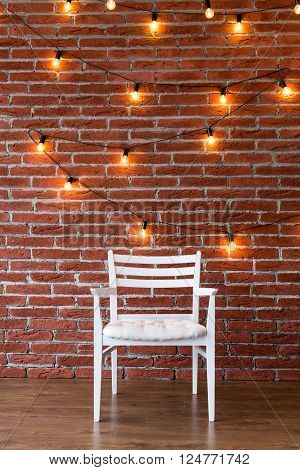 white chair against a background of a brick wall with a garland
