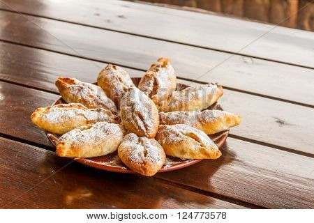 freshly baked apple pies on plate, wooden table