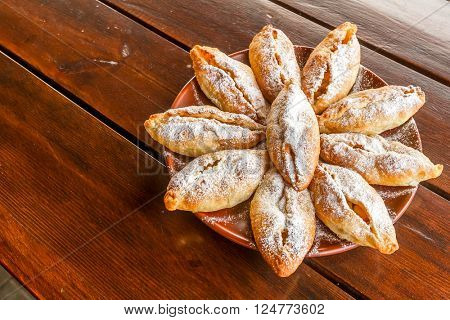 freshly baked apple pies on plate, wooden table