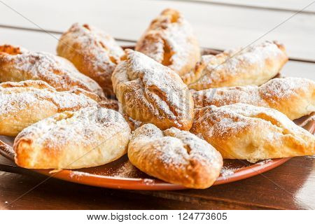 freshly baked apple pies on plate, wooden table