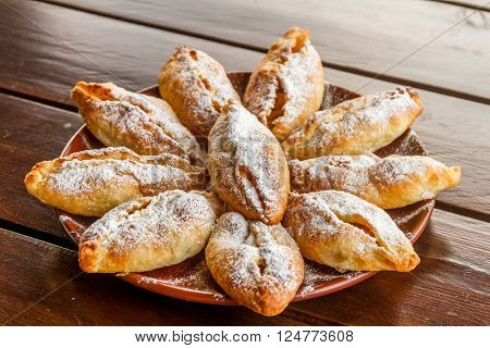 freshly baked apple pies on plate, wooden table