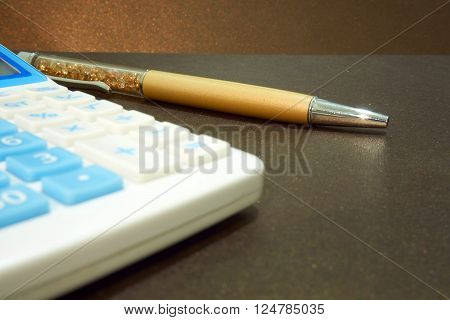 pen and calculator on brown color background
** Note: Shallow depth of field