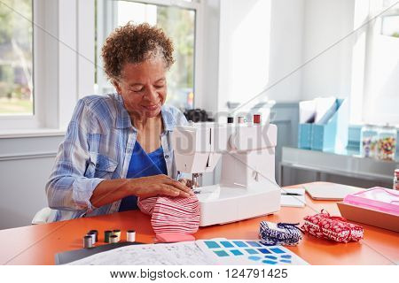 Senior black woman stitching fabric using a sewing machine