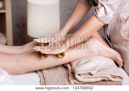 Woman getting feet massage female therapist with bamboo sticks