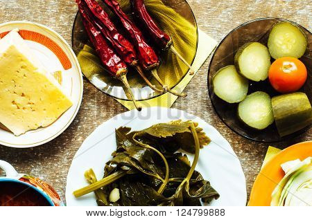 Cucumber marinated bowl with pepper and garlic. Group of fermented veggies on the plate. Overhead view on vegetarian style dinner with vegetable soup pickled cucumbers pickled peppers cabbage.
