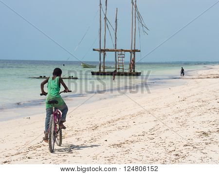 PAJE ZANZIBAR - MARCH 30 2016: Local boy biking on the beach in Zanzibar Tanzania.