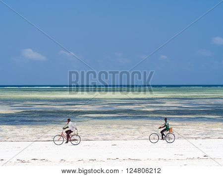 PAJE, ZANZIBAR - MARCH 30, 2016: Local people biking on the beach in Zanzibar, Tanzania.