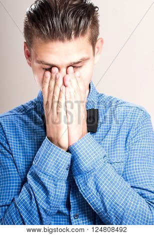 Upset man with eyes closed over gray background.