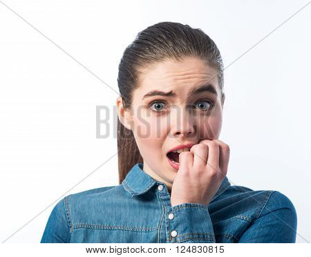 A bit nervous. Neurotic young charming girl  putting her hand in the mouth and looking at you while standing isolated on  white background