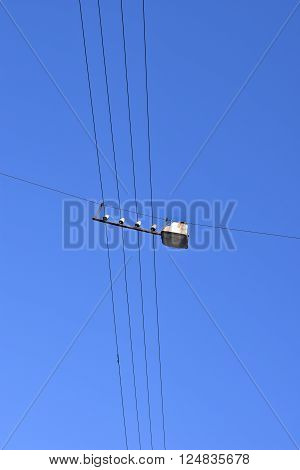 Street lamp hanging on wires on blue sky