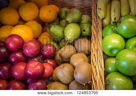 Plums, apples, pears and oranges in a bowl on a table on a self service breakfast counter in a hotel