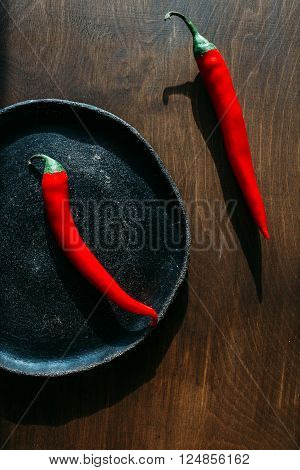 red peppers on a clay plate Two red chili peppers red hot peppers on a brown background red peppers