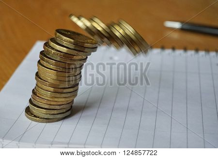 Money background of falling pile of coins made of gold and gilt metal on the paper notepad as a symbol of financial deterioration