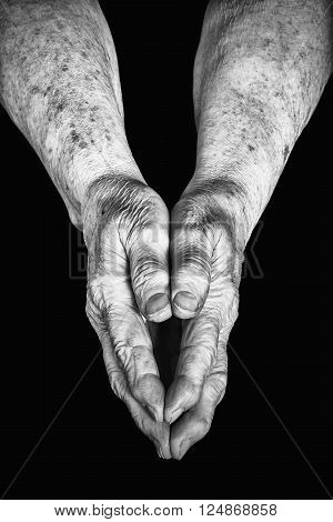 Old woman clasped in her hands on a black background