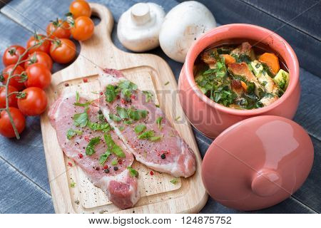 Roasted meat with vegetables in a pot and fresh pork tenderloin with herbs and spices