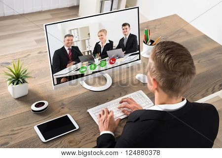 Young Businessman Attending Videoconference On Computer At Office