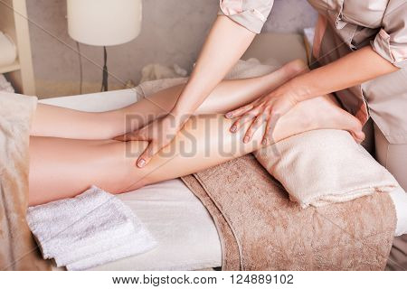 Woman having therapeutic leg massage in spa salon closeup