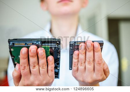 IT specialist hands holding fast flash SSD - solid state drive and Hard Drive Disk HDD