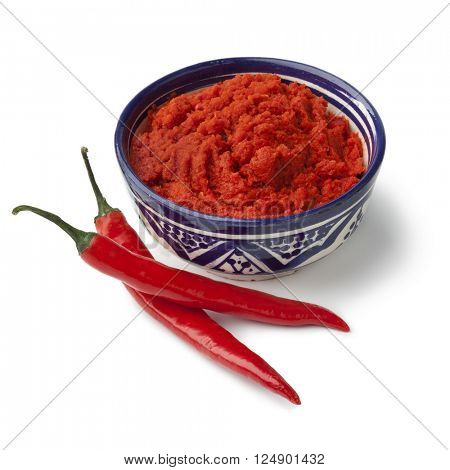 Bowl with red Moroccan harissa and fresh red chili peppers on white background