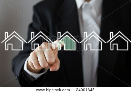 Businessman choosing house, real estate concept. Hand pressing the house icon. Copy space.