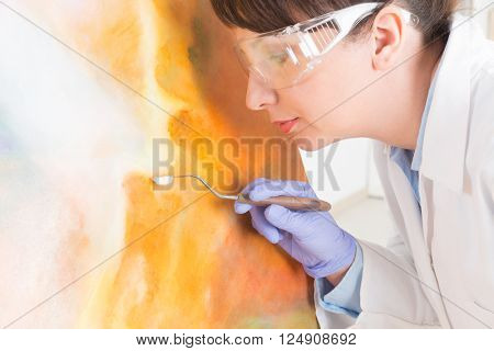 Artwork conservator at work with old painting wearing protective suit