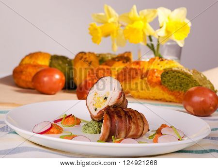Easter meal chicken breast wrapped in bacon with cheese on a plate with vegetables on the table with Easter bread