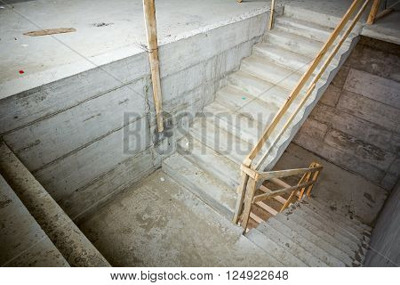 New concrete staircase with temporary wooden handrail under construction.