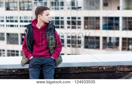 pensive teenager sitting on roof the house