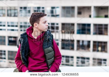 pensive teenager sitting on roof the house
