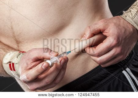 Close up of a muscular man injecting himself with steroids.