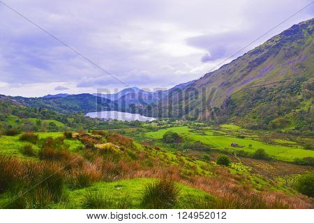 View to a mountain lake and a house in Snowdonia National Park in North Wales of the United Kingdom. Snowdonia is a mountain range and a region in North of Wales.