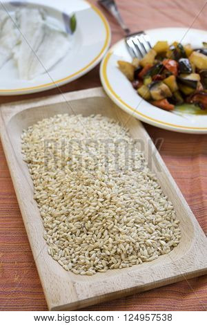 raw organic barley with assorted steamed begetables on a wooden dish