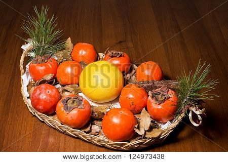 Composition of persimmon grapefruit and pine cone in the dish on table