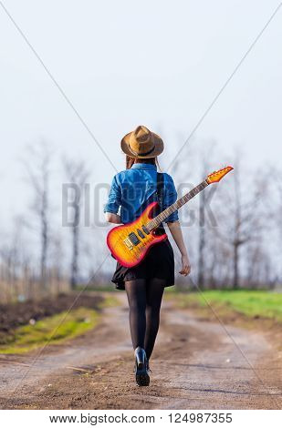 photo of the beautiful young woman with guitar on the road