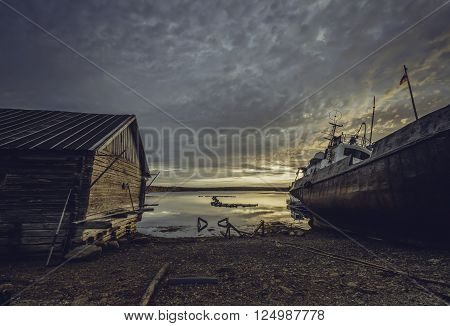 Beautiful sunset with clouds over White Sea with a ship and old house