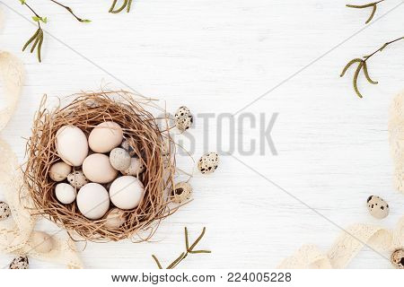 Easter eggs in the nest, Spring willow twigs & Vintage lace on white Retro wooden table. Happy Holidays card in discreet colors. Flat lay, top view.
