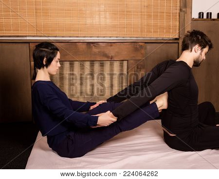 beautiful girl doing thai back massage in spa saloon. Thai massage or Thai yoga massage treatment.