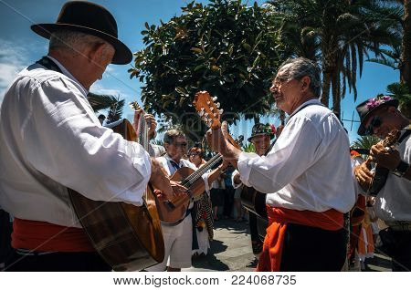 Puerto de la Cruz, Tenerife, Canary Islands - May 30, 2017: Canaries people dressed in traditional clothes walk along the street, sign and play guitars. Local residents of Tenerife celebrate the Day of the Canary Islands.