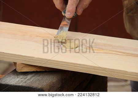 Putty knife in old man's hand. Removing paint from a wood surface. Preparation of boards before impregnation with varnish. Application of putty. Copy space for text.