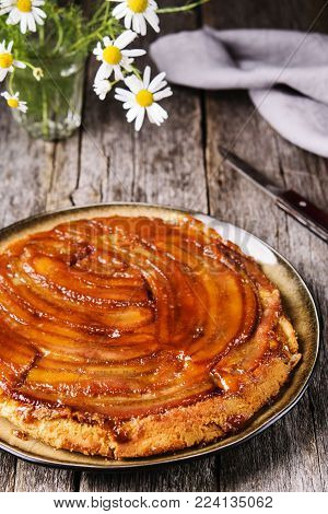 Traditional homemade banana caramel pie on vintage wooden table decorated a bouquet of chamomiles. Upside down banana cake. Selective focus