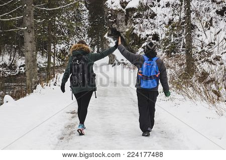 The guy and the girl are walking in the winter forest