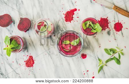 Fresh morning beetroot smoothie or juice in glasses with mint leaves over grey marble background, top view. Healthy vegan, vegetarian breakfast, alcaline diet, weight loss food concept