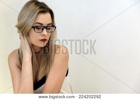 Beautiful blonde with glasses on a light background.
