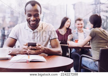 New massage. Afro American jolly male student reading message while preparing task and gazing at the screen