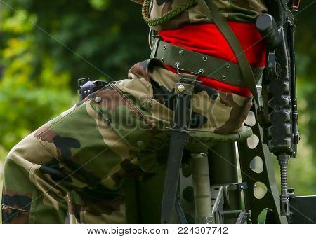 Close-up of military man sitting with arms and ammunition at field