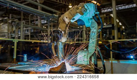 Robot is welding metal part in car factory