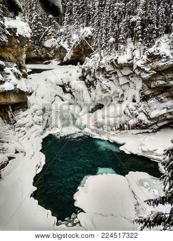 Icy Sunwapta Falls in Winter surrounded my snowy trees