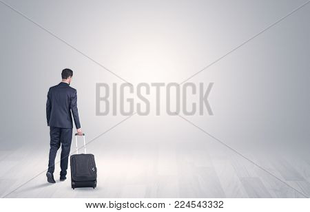 Young businessman in a white boundless space walking with back and luggage on his hand